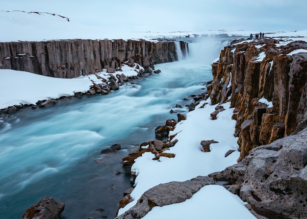 Hermoso tiro de un río en una superficie rocosa nevada