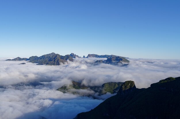 Hermoso tiro de verdes montañas y colinas cubiertas de nubes blancas en un cielo despejado