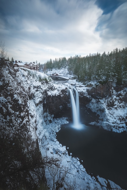 Hermoso tiro vertical de cascadas en la montaña glaciar cerca de árboles en invierno