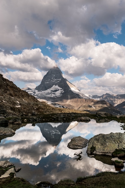 Hermoso tiro vertical de un lago rodeado de montañas con el reflejo de una persona en el agua