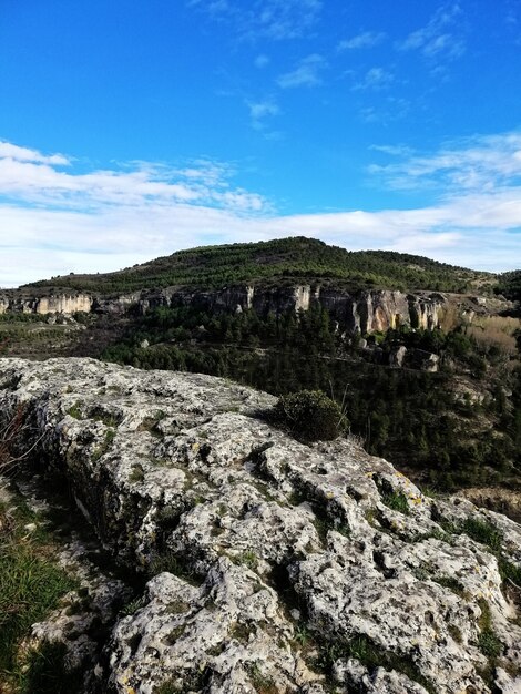 Hermoso tiro vertical de montañas y vegetación bajo un cielo azul en Cuenca España