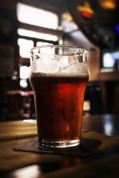 Hermoso vaso de cerveza fría sabrosa oscura en la barra. fondo oscuro.