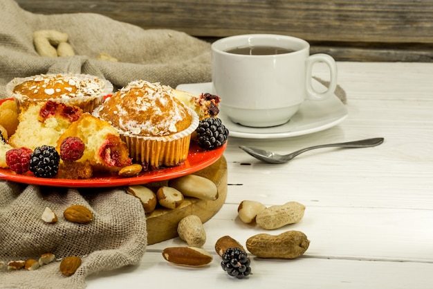 hermosos cupcakes con frutas del bosque en mesa de madera en placa roja