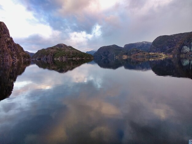 Hermosos fiordos cerca de Bergen, Noruega, con el reflejo de los acantilados y pueblos bajo un cielo nublado