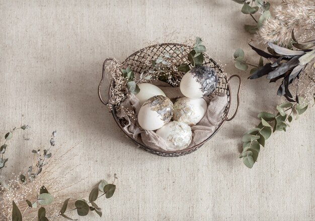 Hermosos huevos de Pascua en una canasta decorada con flores secas. Concepto de Pascua feliz.