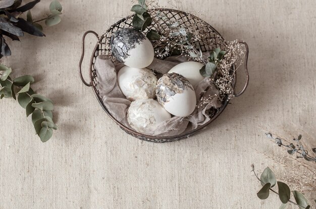 Hermosos huevos de Pascua en una canasta decorada con flores secas. Concepto de Pascua feliz.