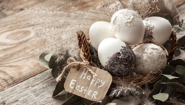 Hermosos huevos de Pascua en una canasta decorada con flores secas. Concepto de Pascua feliz.