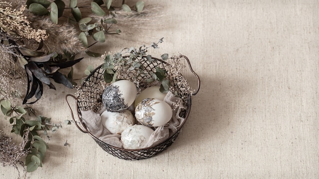 Hermosos huevos de Pascua en una canasta decorada con flores secas. Concepto de Pascua feliz.