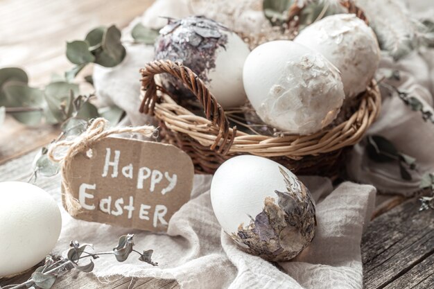 Hermosos huevos de Pascua en una canasta decorada con flores secas. Concepto de Pascua feliz.