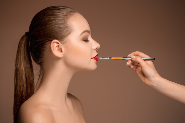 Hermosos labios femeninos con maquillaje y pincel