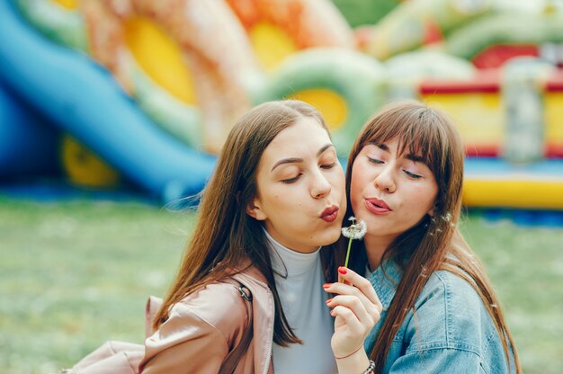 Hermosos ladys descansando en el parque y jugando con el diente de león.