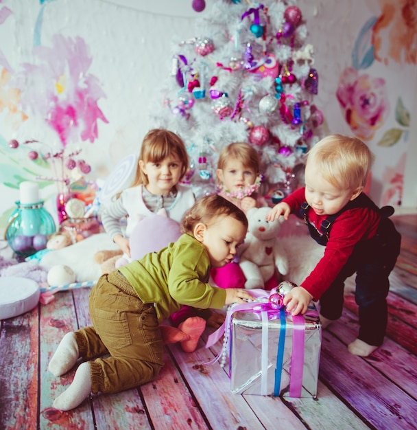 Los hermosos niños sentados cerca del árbol de Navidad