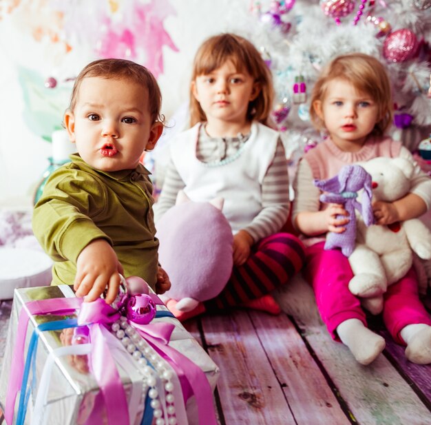 Los hermosos niños sentados cerca del árbol de Navidad