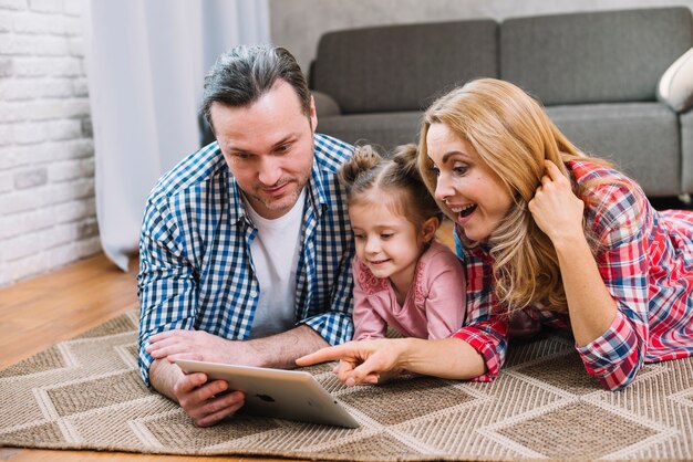 Hermosos padres felices con su pequeña hija usando tableta digital