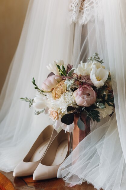 Hermosos zapatos de boda, vestido y ramo de flores.