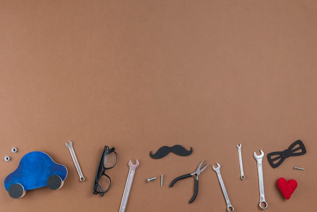 Herramientas con bigote de papel, gafas y coche de juguete.