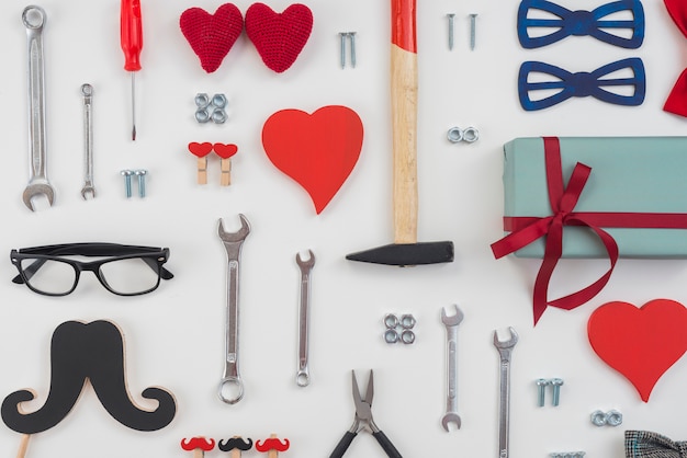 Foto gratuita herramientas con caja de regalo, bigote negro y corazones rojos.