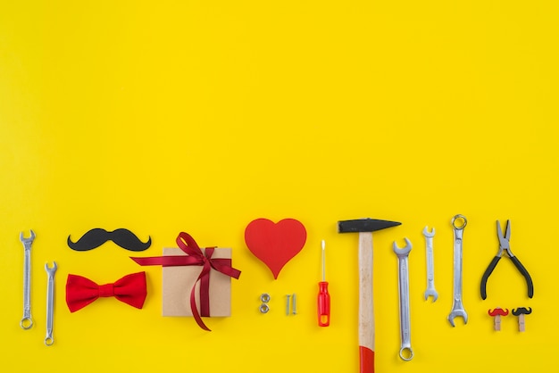 Herramientas con caja de regalo, bigote de papel y corazón rojo.