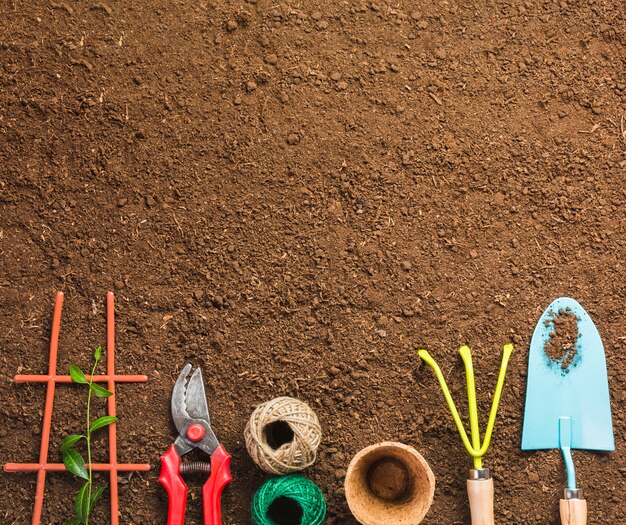 Herramientas de jardinería sobre la tierra vista desde arriba