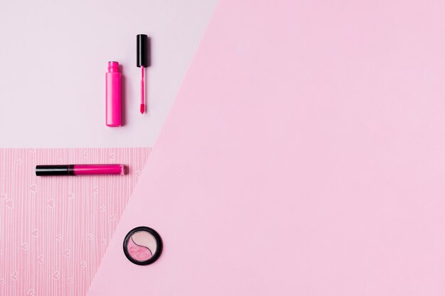 Herramientas de maquillaje en superficie rosa.