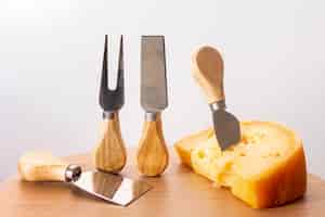 Foto gratuita herramientas de primer plano con una rodaja de queso sobre una mesa