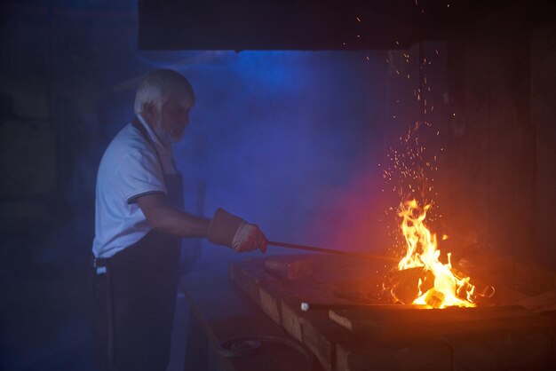 Herrero hábil calentando acero sobre fuego ardiente