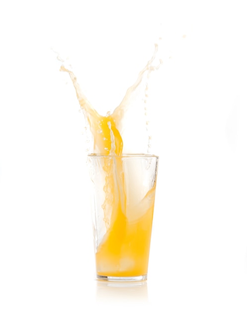 Hielo cayendo dentro de un vaso con bebida amarilla