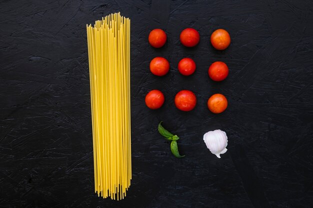 Hierba y ajo cerca de pasta y tomates