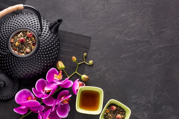 Hierba de té seco saludable y hermosa flor rosa orquídea sobre fondo negro