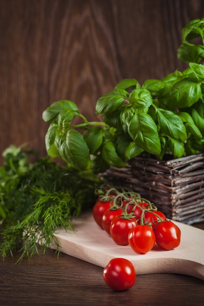 Hierba verde y ramita de tomates cherry en madera