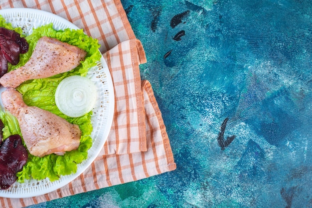 Hígado de pollo, hojas de lechuga y muslo de pollo en un plato sobre el paño de cocina