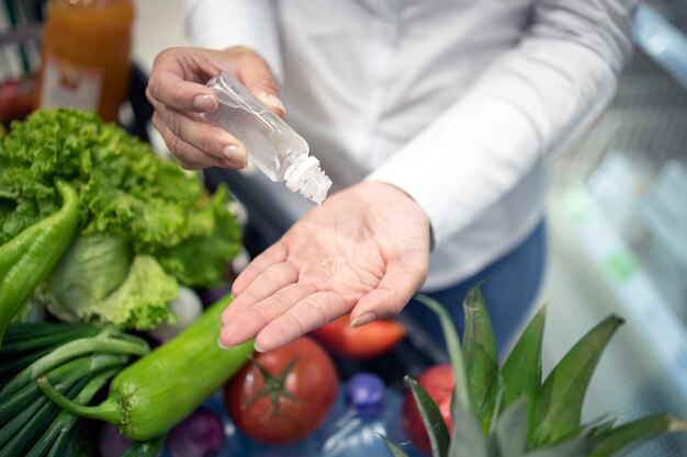 Higienización de manos contra el virus corona mientras compra en el supermercado