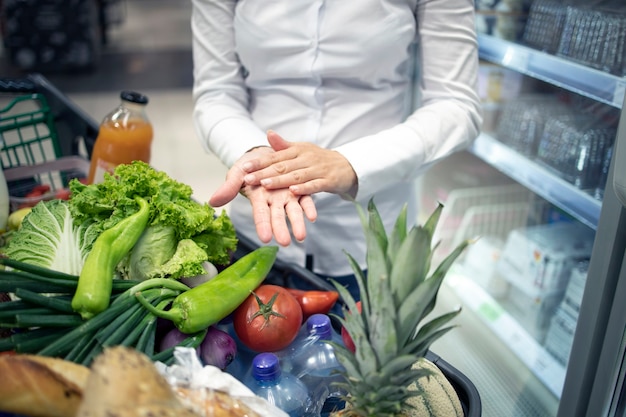 Higienización de manos contra el virus corona mientras compra en el supermercado