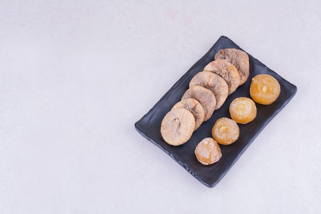 Higos secos y cerezas en plato de cerámica.