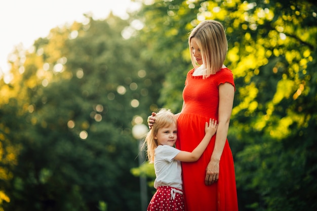 Hija abrazando a su madre embarazada