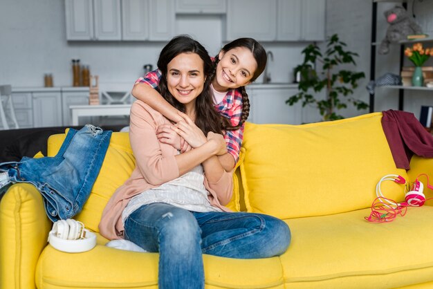 Hija abrazando a su madre en el sofá