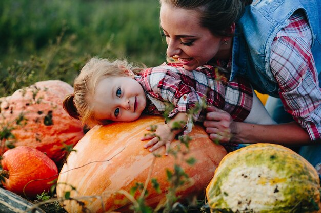 Hija acostada sobre una calabaza y su madre de pie junto a