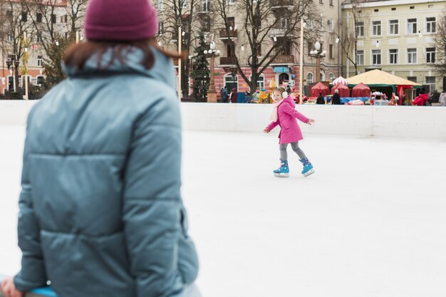 Hija adorable patinaje sobre hielo al aire libre