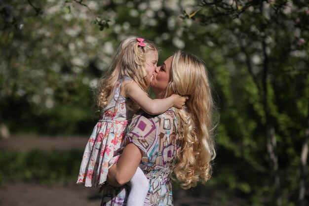 Hija besa a mamá en el jardín.