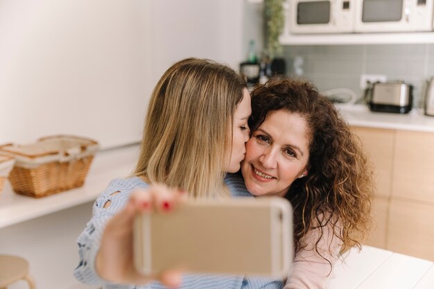 Hija besando a mamá mientras toma selfie