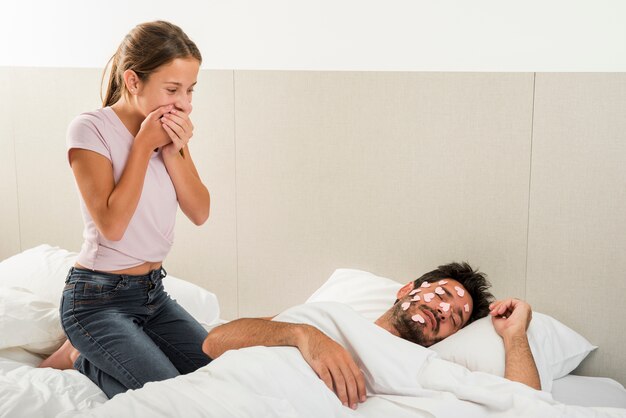 Hija colocando corazones en padre durmiendo