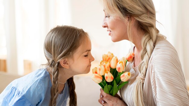 Hija dando a madre ramo de tulipanes como presente