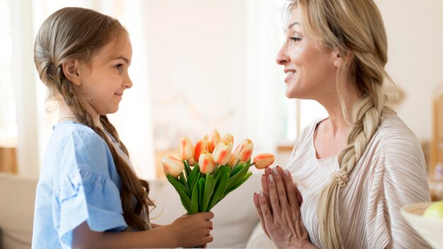 Hija dando a madre ramo de tulipanes como regalo