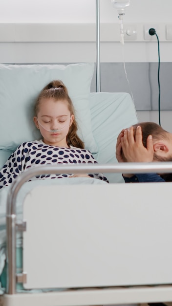 Hija enferma hospitalizada durmiendo después de sufrir una cirugía médica