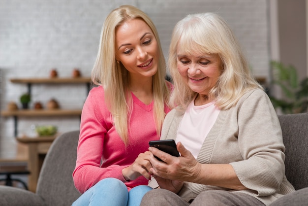 Hija enseñando a su madre a usar el teléfono inteligente