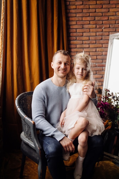 Hija feliz de la familia que abraza a papá y se ríe en día de fiesta