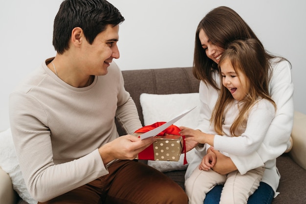 Hija feliz recibiendo regalo de los padres en casa