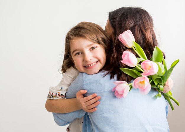 Hija feliz con tulipanes abrazando a la madre