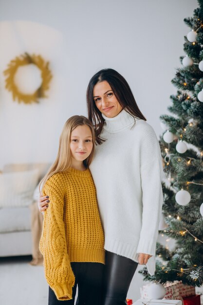 Hija con madre por el árbol de navidad