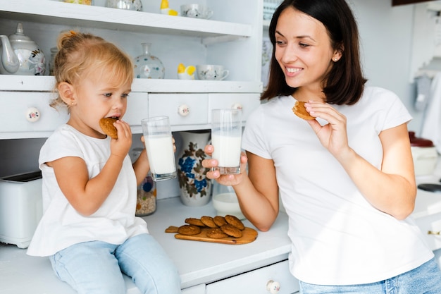 Hija y madre bebiendo leche y comiendo galletas